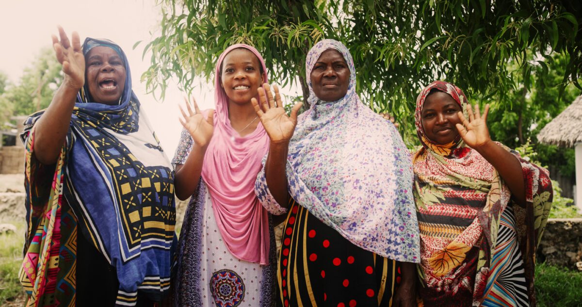 A Group of Authentic African Women in Traditional Clothes Waving and Smiling at the Camera. Friendly Female Rural Villagers Welcoming People in their Village with Big Smiles and Open Hearts VolunteerForever